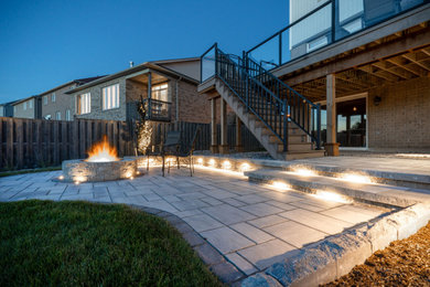Photo of a mid-sized modern full sun backyard concrete paver and wood fence landscaping in Other with a fire pit for summer.