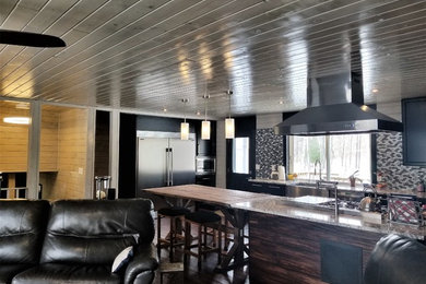Open concept kitchen - farmhouse dark wood floor open concept kitchen idea in Minneapolis with a farmhouse sink, black cabinets, granite countertops, gray backsplash, mosaic tile backsplash, stainless steel appliances, an island and recessed-panel cabinets