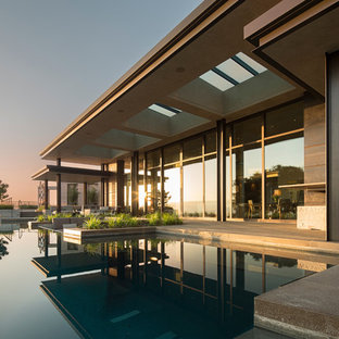 Moderner Infinity-Pool hinter dem Haus in individueller Form mit Betonplatten in Sonstige