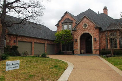 Inspiration for a large french country red two-story brick and shingle exterior home remodel in Dallas with a shingle roof and a black roof