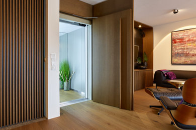 Modelo de salón para visitas cerrado contemporáneo extra grande con paredes blancas, suelo de madera clara, televisor retractable, suelo marrón y madera