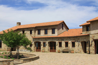На фото: большой, двухэтажный частный загородный дом в средиземноморском стиле с облицовкой из камня, двускатной крышей, черепичной крышей и красной крышей с