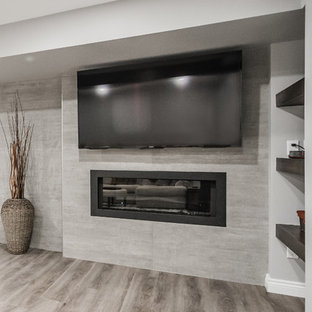 Imagen de sótano con ventanas tradicional renovado, grande, con paredes grises, suelo vinílico, chimeneas suspendidas, marco de chimenea de hormigón y suelo marrón