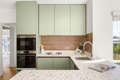 Inspiration for a small midcentury u-shaped separate kitchen in Sydney with a double-bowl sink, green cabinets, terrazzo benchtops, brown splashback, ceramic splashback, stainless steel appliances, laminate floors, beige floor and beige benchtop.