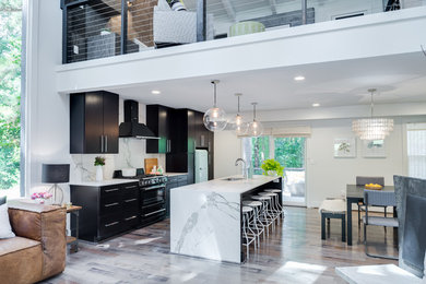 Design ideas for a large contemporary galley open plan kitchen in Atlanta with an undermount sink, with island, flat-panel cabinets, black cabinets, marble benchtops, grey splashback, stone slab splashback, stainless steel appliances and light hardwood floors.