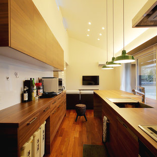 Foto di una cucina etnica con lavello a vasca singola, ante lisce, ante in legno scuro, top in legno, pavimento in legno massello medio, isola e pavimento marrone