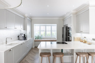 Design ideas for a contemporary kitchen/diner in Sussex with shaker cabinets, grey cabinets, quartz worktops, white splashback and a breakfast bar.