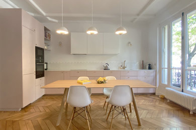 Cette image montre une grande cuisine américaine minimaliste en L avec des portes de placard rose, un plan de travail en quartz, une crédence blanche, une crédence en céramique, aucun îlot et un plan de travail blanc.