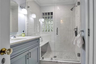 Shower bench - mid-sized traditional white tile and ceramic tile marble floor, gray floor and single-sink shower bench idea in New York with recessed-panel cabinets, gray cabinets, gray walls, an undermount sink, marble countertops, a hinged shower door, gray countertops and a freestanding vanity