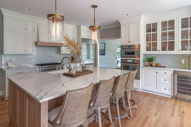 Large elegant l-shaped light wood floor and beige floor open concept kitchen photo in Other with a farmhouse sink, beaded inset cabinets, white cabinets, quartz countertops, white backsplash, quartz backsplash, stainless steel appliances, an island and white countertops