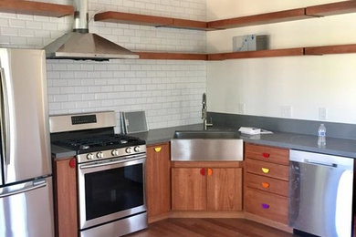Enclosed kitchen - mid-sized craftsman l-shaped medium tone wood floor and brown floor enclosed kitchen idea in San Francisco with a farmhouse sink, flat-panel cabinets, medium tone wood cabinets, soapstone countertops, white backsplash, subway tile backsplash, stainless steel appliances, no island and black countertops