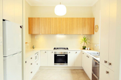 This is an example of a small contemporary u-shaped separate kitchen in Melbourne with a double-bowl sink, flat-panel cabinets, white cabinets, granite benchtops, beige splashback, glass sheet splashback, stainless steel appliances, limestone floors and no island.