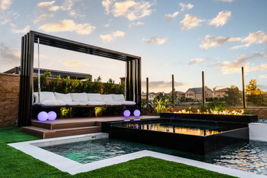 Ejemplo de piscina minimalista de tamaño medio en forma de L en patio trasero con suelo de baldosas