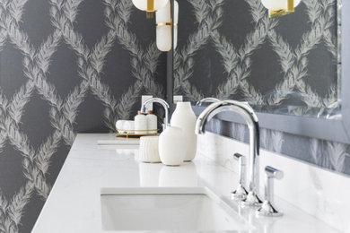 Powder room - large french country white tile and stone tile marble floor, white floor and wallpaper powder room idea in Philadelphia with raised-panel cabinets, white cabinets, gray walls, an undermount sink, quartz countertops, white countertops and a built-in vanity