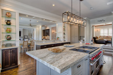 Mid-sized transitional eat-in kitchen in New York with a drop-in sink, flat-panel cabinets, blue cabinets, stainless steel appliances, dark hardwood floors, with island and marble benchtops.