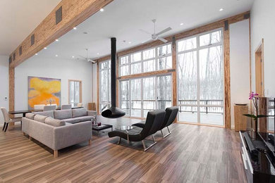 This is an example of a modern open concept living room in Ottawa with white walls, medium hardwood floors and a hanging fireplace.