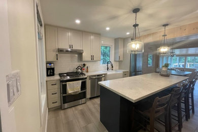 Kitchen - rustic single-wall kitchen idea in Toronto with shaker cabinets, white backsplash, stainless steel appliances, an island and white countertops