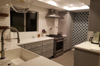 Inspiration for a mid-sized transitional l-shaped porcelain tile and gray floor enclosed kitchen remodel in Los Angeles with a farmhouse sink, shaker cabinets, gray cabinets, quartz countertops, white backsplash, ceramic backsplash, stainless steel appliances and no island