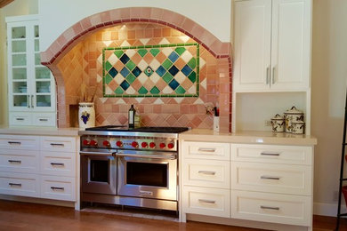 Inspiration for a mid-sized mediterranean light wood floor and beige floor kitchen remodel in San Francisco with beaded inset cabinets, white cabinets, brown backsplash, ceramic backsplash, stainless steel appliances and beige countertops