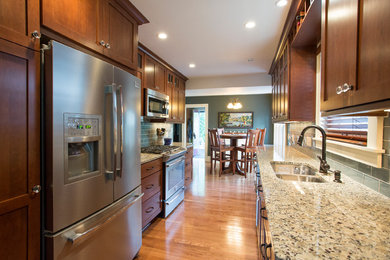 Inspiration for a mid-sized eclectic galley medium tone wood floor eat-in kitchen remodel in Minneapolis with a double-bowl sink, shaker cabinets, dark wood cabinets, granite countertops, blue backsplash, subway tile backsplash, stainless steel appliances and no island