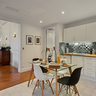 Ejemplo de cocina en L, actual, grande, abierta, con armarios con rebordes decorativos, puertas de armario blancas, encimera de madera, salpicadero de azulejos de cemento, electrodomésticos blancos, suelo de baldosas de cerámica, fregadero encastrado y salpicadero multicolor