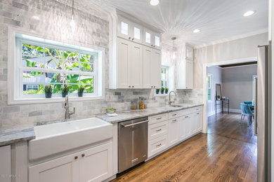 Inspiration for a mediterranean medium tone wood floor and brown floor kitchen remodel in Jacksonville with a farmhouse sink, shaker cabinets, white cabinets, marble countertops, gray backsplash, marble backsplash and stainless steel appliances