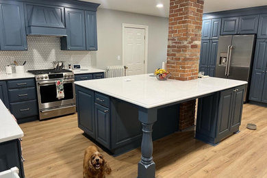 Kitchen - traditional kitchen idea in Portland Maine with raised-panel cabinets, blue cabinets, quartz countertops, white backsplash, mosaic tile backsplash, stainless steel appliances and white countertops
