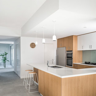 Moderne Küche in U-Form mit Vorratsschrank, hellen Holzschränken, Quarzwerkstein-Arbeitsplatte, Glasrückwand, Küchengeräten aus Edelstahl, Keramikboden, grauem Boden, weißer Arbeitsplatte, Doppelwaschbecken, flächenbündigen Schrankfronten, Küchenrückwand in Grün und Halbinsel in Perth