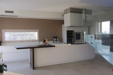 Foto di una grande cucina moderna con lavello integrato, ante lisce, ante bianche, top in superficie solida, elettrodomestici in acciaio inossidabile, pavimento in cemento, pavimento beige e top bianco