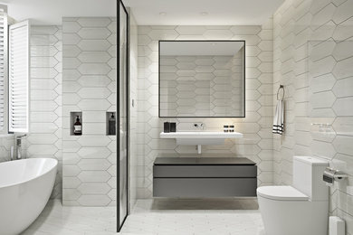 Inspiration for a large contemporary master white tile and marble tile marble floor and white floor bathroom remodel in New York with flat-panel cabinets, brown cabinets, a wall-mount toilet, white walls and an integrated sink