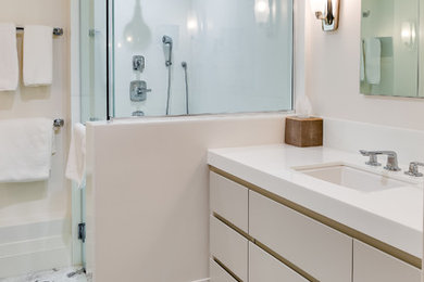 Mid-sized minimalist master marble floor corner shower photo in Miami with flat-panel cabinets, beige cabinets, an undermount sink and solid surface countertops