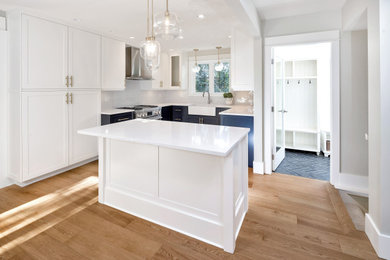 Eat-in kitchen - large transitional l-shaped medium tone wood floor eat-in kitchen idea in Other with a farmhouse sink, shaker cabinets, blue cabinets, quartz countertops, white backsplash, subway tile backsplash, stainless steel appliances, an island and white countertops
