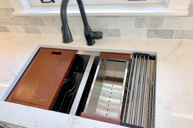 Open concept kitchen - mid-sized modern light wood floor and brown floor open concept kitchen idea in Chicago with a double-bowl sink, shaker cabinets, white cabinets, quartzite countertops, gray backsplash, marble backsplash, stainless steel appliances, an island and white countertops