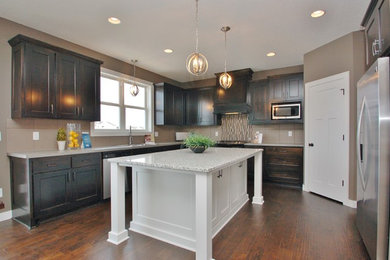 Kitchen - traditional dark wood floor kitchen idea in Minneapolis with a drop-in sink, shaker cabinets, dark wood cabinets, granite countertops, beige backsplash, ceramic backsplash, stainless steel appliances and an island
