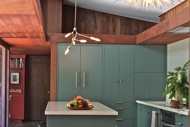 This is an example of a midcentury l-shaped kitchen in San Francisco with an undermount sink, flat-panel cabinets, green cabinets, solid surface benchtops, grey splashback and with island.