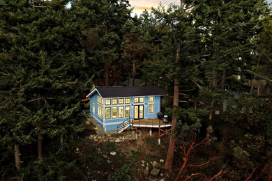 Foto della micro casa piccola blu stile marinaro a un piano con rivestimento in legno, falda a timpano, copertura in metallo o lamiera e tetto marrone