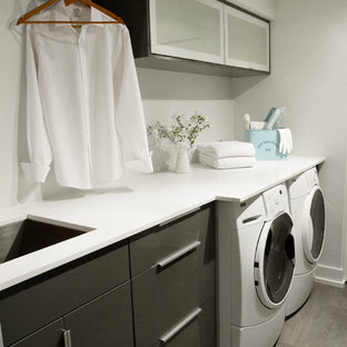 Photo of a modern galley utility room in Vancouver with vinyl flooring, a submerged sink, a side by side washer and dryer, engineered stone countertops, grey cabinets and flat-panel cabinets.