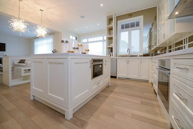 Photo of a large contemporary u-shaped eat-in kitchen in Toronto with an undermount sink, shaker cabinets, white cabinets, quartz benchtops, grey splashback, white appliances, dark hardwood floors, multiple islands and brown floor.