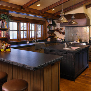 Large rustic enclosed kitchen pictures - Inspiration for a large rustic u-shaped dark wood floor enclosed kitchen remodel in Boise with a farmhouse sink, stainless steel appliances, an island, shaker cabinets, soapstone countertops, gray backsplash and dark wood cabinets