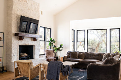 Living room - large farmhouse open concept medium tone wood floor and vaulted ceiling living room idea in Austin with white walls, a standard fireplace, a stone fireplace and a wall-mounted tv