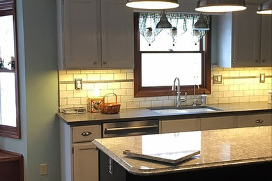 Enclosed kitchen - mid-sized transitional u-shaped medium tone wood floor enclosed kitchen idea in Other with an undermount sink, white cabinets, quartz countertops, white backsplash, subway tile backsplash, stainless steel appliances and an island