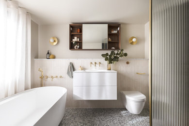 Photo of a contemporary ensuite bathroom in London with white cabinets, a freestanding bath, a walk-in shower, a wall mounted toilet, terrazzo flooring, an open shower and a single sink.