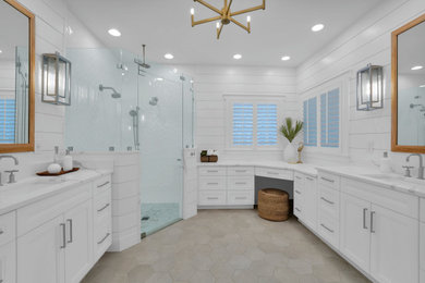 Corner shower - large coastal master white tile and ceramic tile double-sink corner shower idea in Jacksonville with recessed-panel cabinets, white cabinets, quartz countertops, a hinged shower door, white countertops, a niche and a built-in vanity