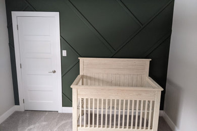 Diseño de habitación de bebé niño actual de tamaño medio con paredes verdes, moqueta, suelo beige y boiserie