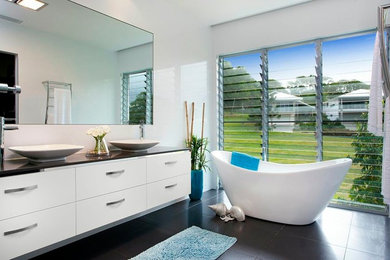 Photo of an expansive contemporary master bathroom in Sunshine Coast with a vessel sink, flat-panel cabinets, white cabinets, engineered quartz benchtops, a freestanding tub, black tile, ceramic tile, white walls and ceramic floors.