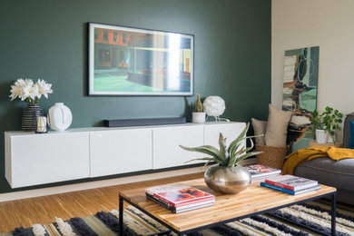 Immagine di un soggiorno contemporaneo aperto e di medie dimensioni con parquet chiaro, pareti verdi e TV a parete