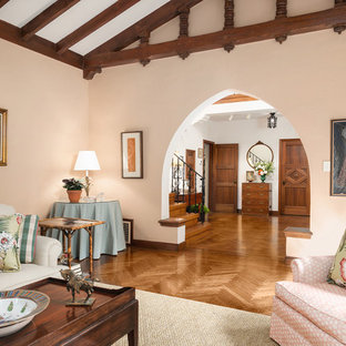 Diseño de salón para visitas cerrado, mediterráneo, grande, con paredes rosas, suelo de madera en tonos medios, chimenea tradicional, marco de chimenea de madera y suelo marrón