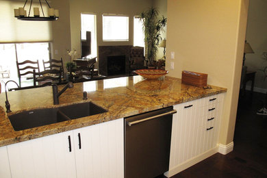 Example of a mid-sized transitional u-shaped dark wood floor enclosed kitchen design in Denver with a double-bowl sink, white cabinets, yellow backsplash, stainless steel appliances and no island