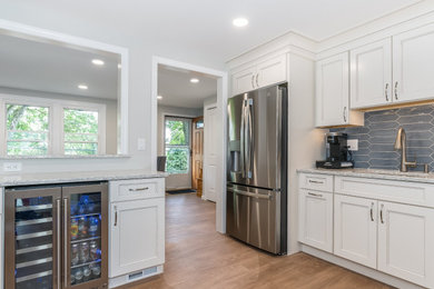 Mid-sized transitional l-shaped medium tone wood floor and brown floor eat-in kitchen photo in New York with an undermount sink, recessed-panel cabinets, white cabinets, quartz countertops, gray backsplash, glass tile backsplash, stainless steel appliances and gray countertops