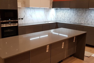 This is an example of a large l-shaped kitchen in Other with a double-bowl sink, grey cabinets, engineered stone countertops, an island and grey worktops.